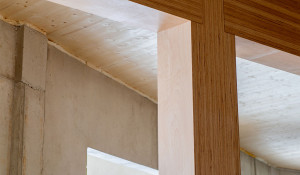 Holzhybridbau im Detail: Tragende Holzstützen treffen auf massive Bauteile und schaffen eine stabile Kombination.